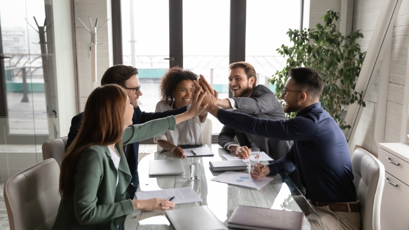 Team celebrating success with a group high-five in a meeting room