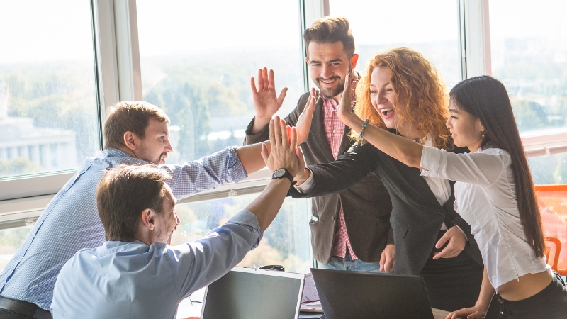 A team of colleagues celebrates success with high fives, symbolizing real-world examples of scaling up in business