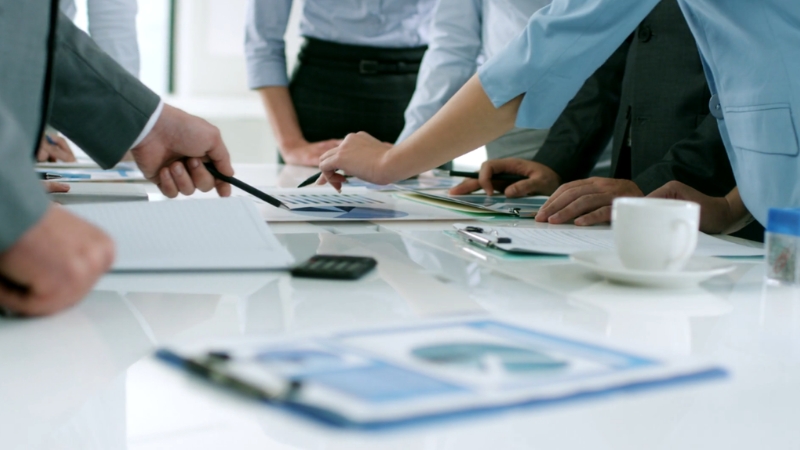 Business leaders collaborate around documents and charts during a level 10 meeting focused on EOS strategy