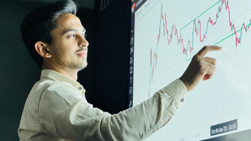 A man points at a chart on a screen while explaining data trends related to the available market