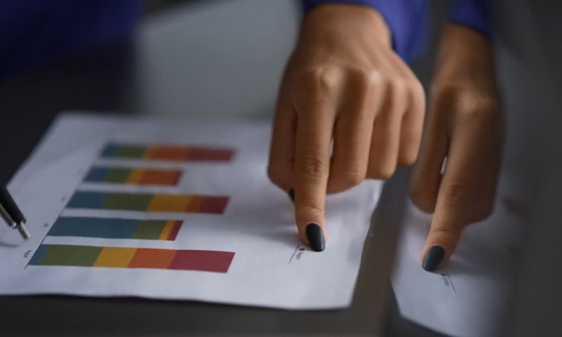 Businesswoman's hands resting on a paper covered with various graphs and data visualizations