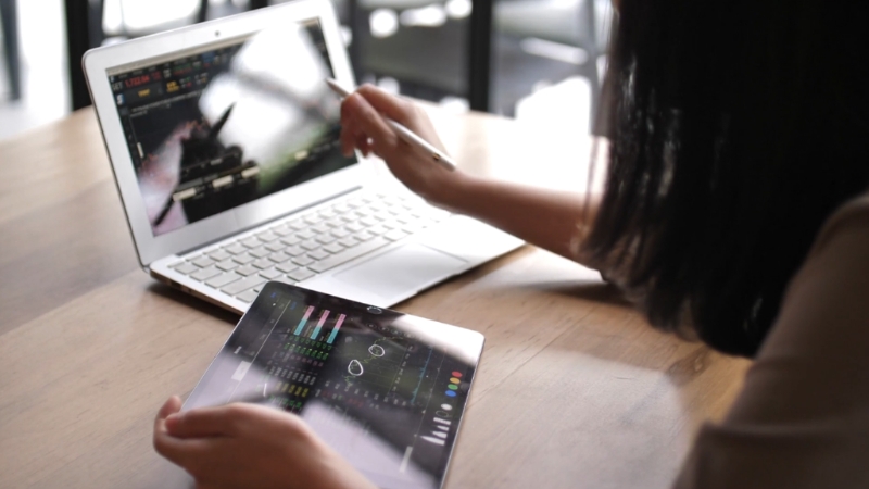 A woman works on a tablet and laptop displaying market charts to analyze available market potential