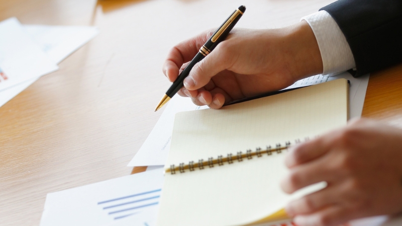 A person takes notes while reviewing business charts and data related to a Product Matrix Strategy