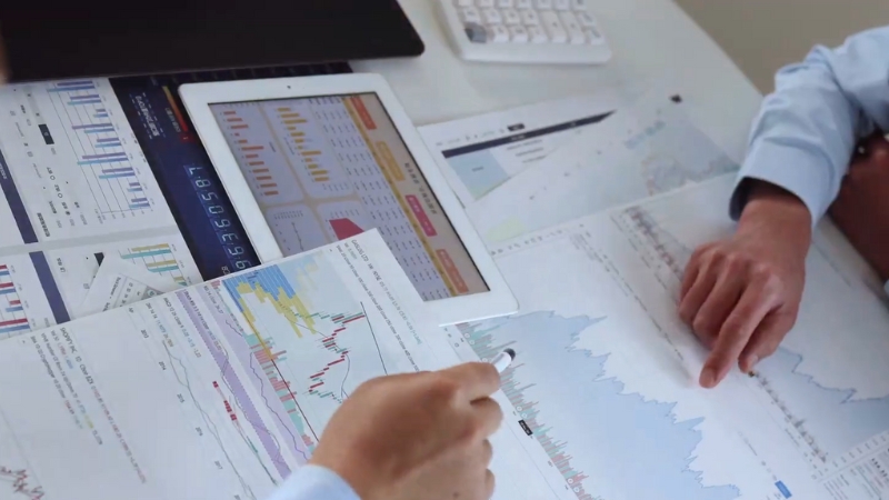 Two professionals review charts and graphs while analyzing the SCP model