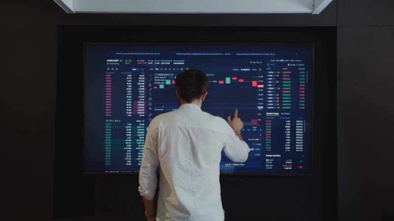 A man analyzing financial charts on a large screen to evaluate the performance of a company’s economic engine