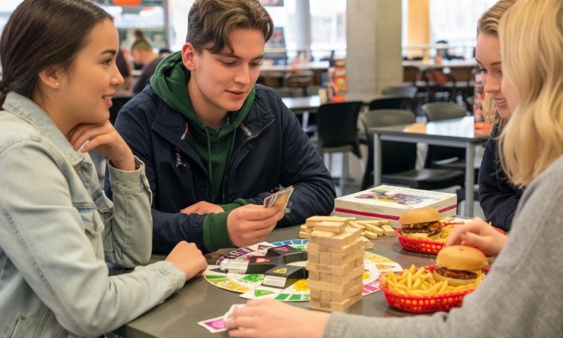 Three students engaged in a board game at a table