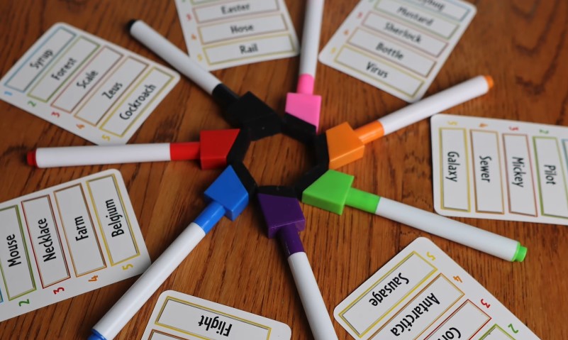 A circle of colorful markers and writing cards, set up for a board game activity