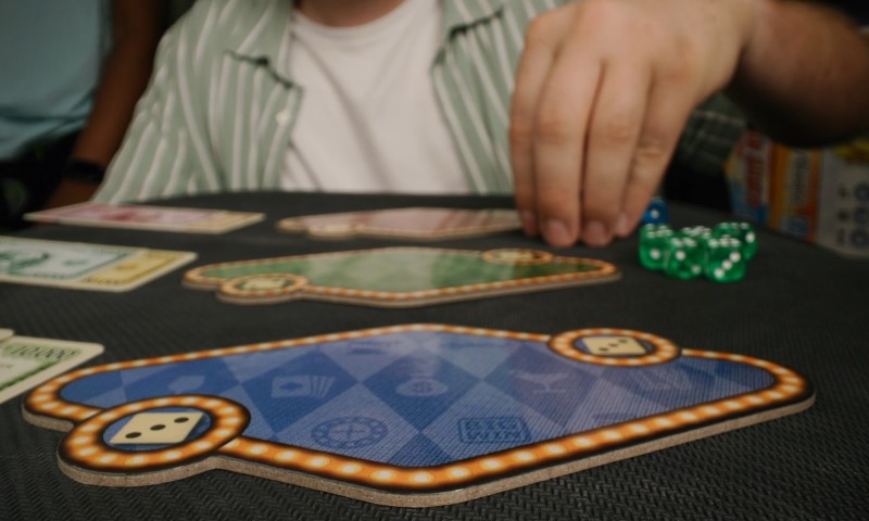 A man playing board game, rolling dice and on a colorful setup