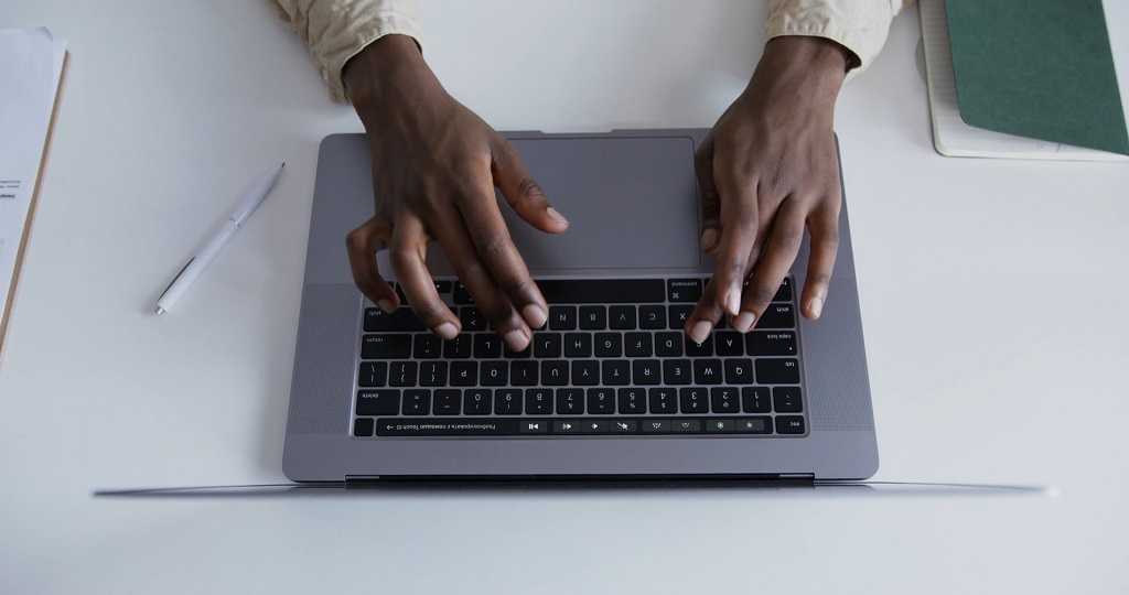 Hands typing on a laptop keyboard while working on a business or marketing task.