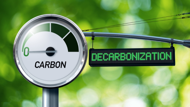 Carbon meter indicator next to a digital sign reading decarbonization against a green background