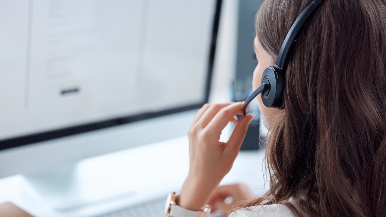 Woman wearing a headset works at a computer, handling a customer service call