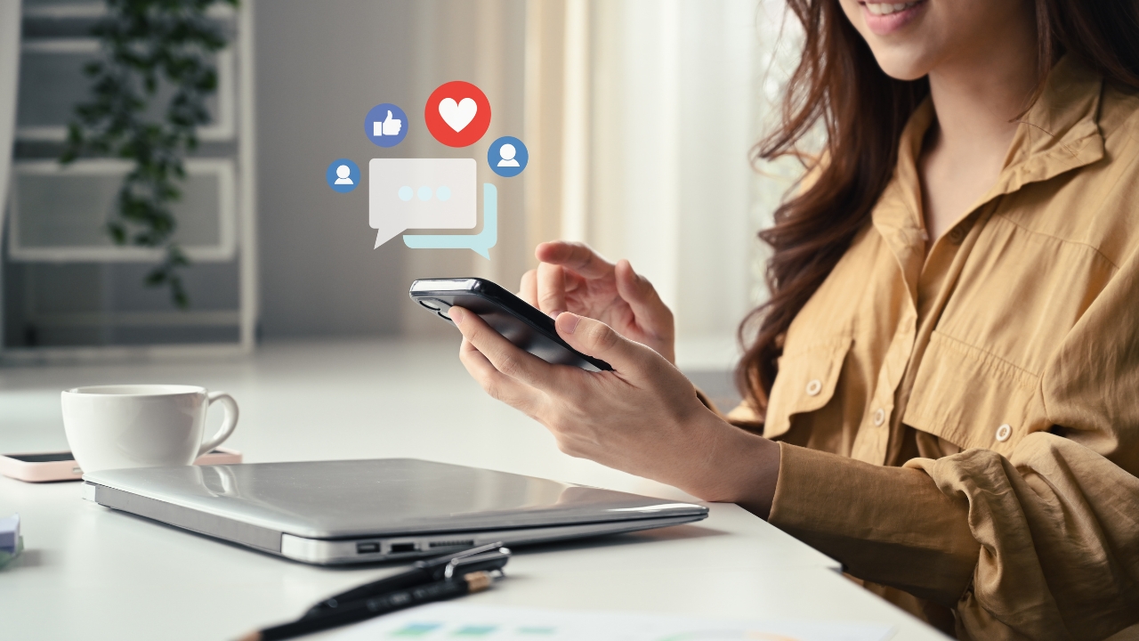 Woman uses her phone for social media with engagement icons above the screen